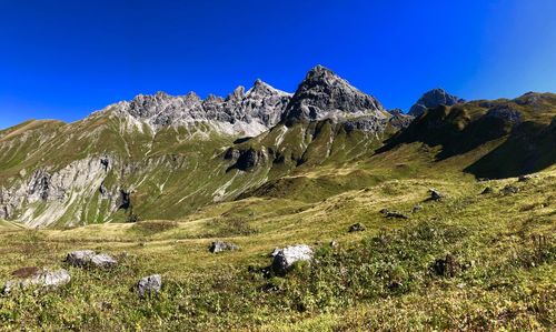 Scenic view of landscape and mountains against blue sky