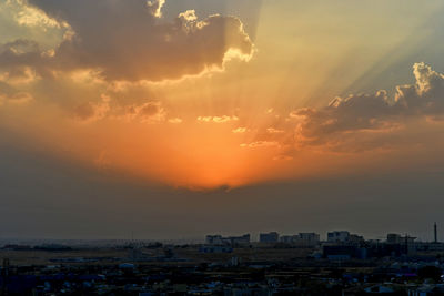 Aerial view of city by sea against sky during sunset