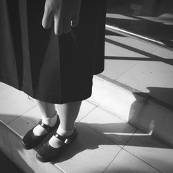 Low section of girl wearing school uniform standing on tiled floor