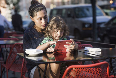 Family using tablet computer at sidewalk cafe