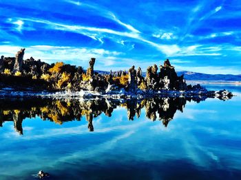 Reflection of tree in lake against blue sky