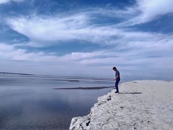 Side view of man standing in sea against sky