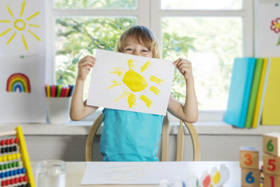 Funny beautiful happy child boy draws laughing with paint.