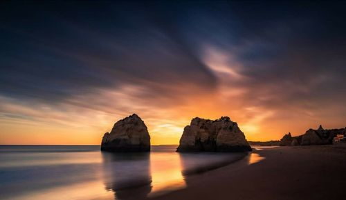 Scenic view of sea against dramatic sky during sunset