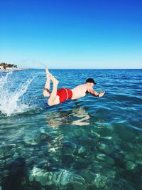 Full length of shirtless man diving into sea