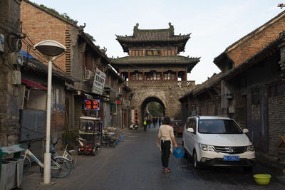 Rear view of people walking on street amidst buildings in city