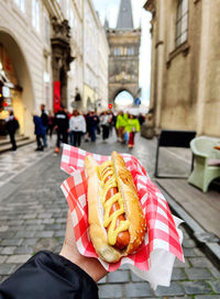 Close-up hand holds hotdog buns over street in prague 