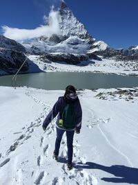 Rear view of woman walking on snow covered lakeshore