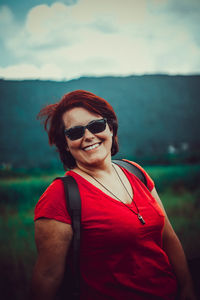 Portrait of smiling man wearing sunglasses standing against sky