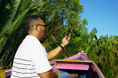 Man holding equipment against trees