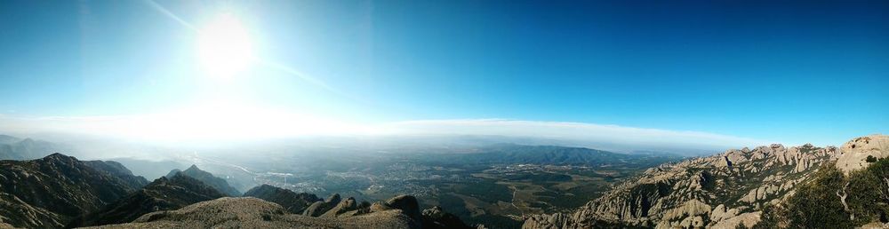 Scenic view of mountains against blue sky on sunny day