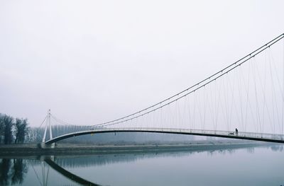 Suspension bridge over river against clear sky