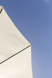 Low angle view of parasol against clear blue sky