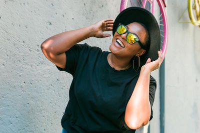 Portrait of young woman standing against wall