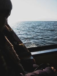 Man sitting by sea against clear sky