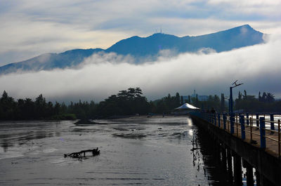 Scenic view of river by mountains against sky