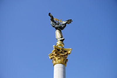 Low angle view of angel statue against blue sky