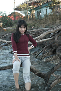 Portrait of teenage girl sitting on tree branch in river