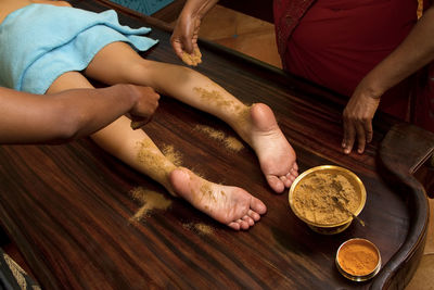 Massage therapists pouring turmeric on woman at spa