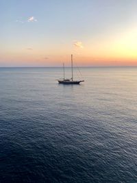 Sailboat sailing on sea against sky during sunset