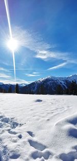 Scenic view of snow covered mountains against bright sun