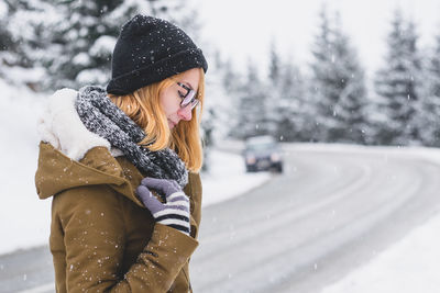 Woman in warm clothing standing on road during snowfall