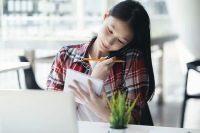 Portrait of woman using phone while sitting on table