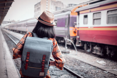 Rear view of woman standing on railroad track