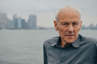 Close-up portrait of senior man against city