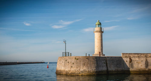 Lighthouse by sea against sky