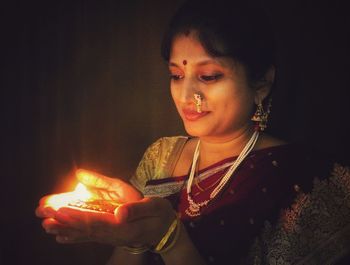 Close-up of woman holding diya in dark