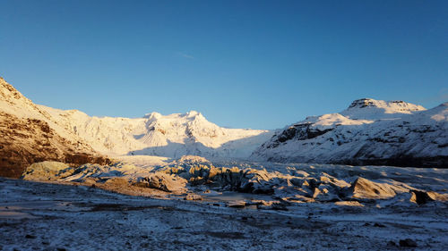 Scenic view of snowcapped mountains against clear blue sky