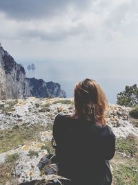 Rear view of woman looking at sea against cloudy sky