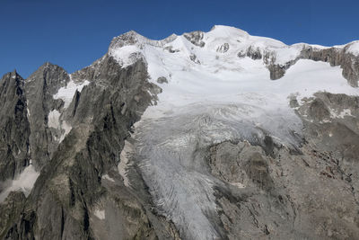 Scenic view of snowcapped mountains against sky on sunny day