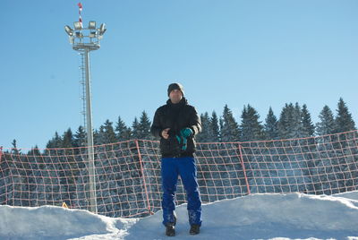 Full length of man standing on snow against clear blue sky