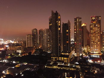 Illuminated buildings in city against sky at night