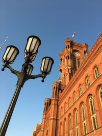 Low angle view of street light by building against clear sky