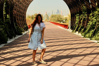 Full length of young woman standing on footpath