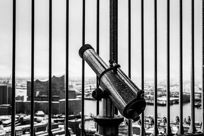 Hand-held telescope by fence in city