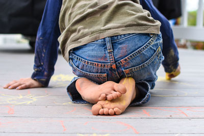 Rear view of boy doing chalk drawing on floorboard