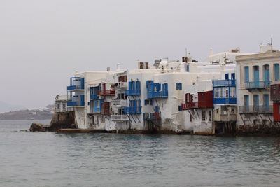 Buildings by sea against clear sky