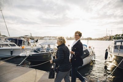 Happy senior women walking on pier by moored boats