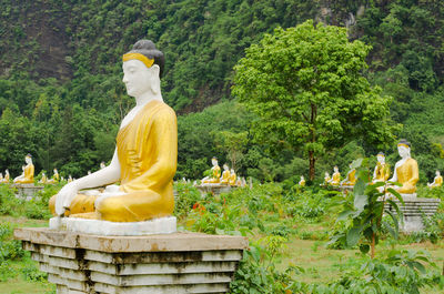 Statue of buddha sitting against trees