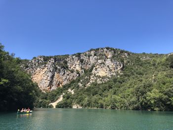 Scenic view of lake and mountains against clear blue sky