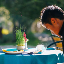 Close-up of dining table with tea and succulent plant against man in background at restaurant