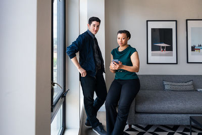 Portrait of businesswoman holding mobile phone while standing with coworker at office