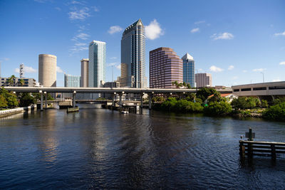 Bridge over river by buildings against sky in city