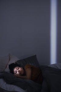 Pensive young woman lying in bed