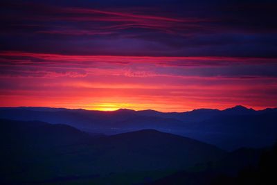 Scenic view of silhouette mountains against orange sky