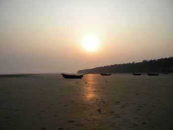 View of boats on beach at sunset